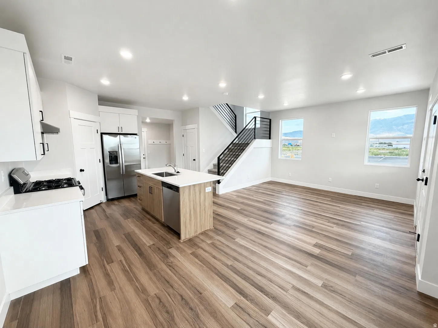 Open-concept living space featuring wood-finish flooring, recessed lighting, and large windows with mountain scenery