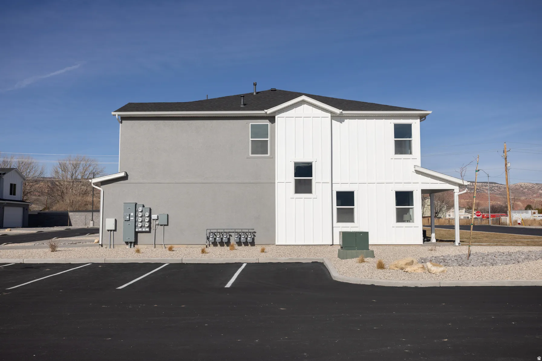 Modern two-story structure featuring a combination of gray stucco and white vertical siding