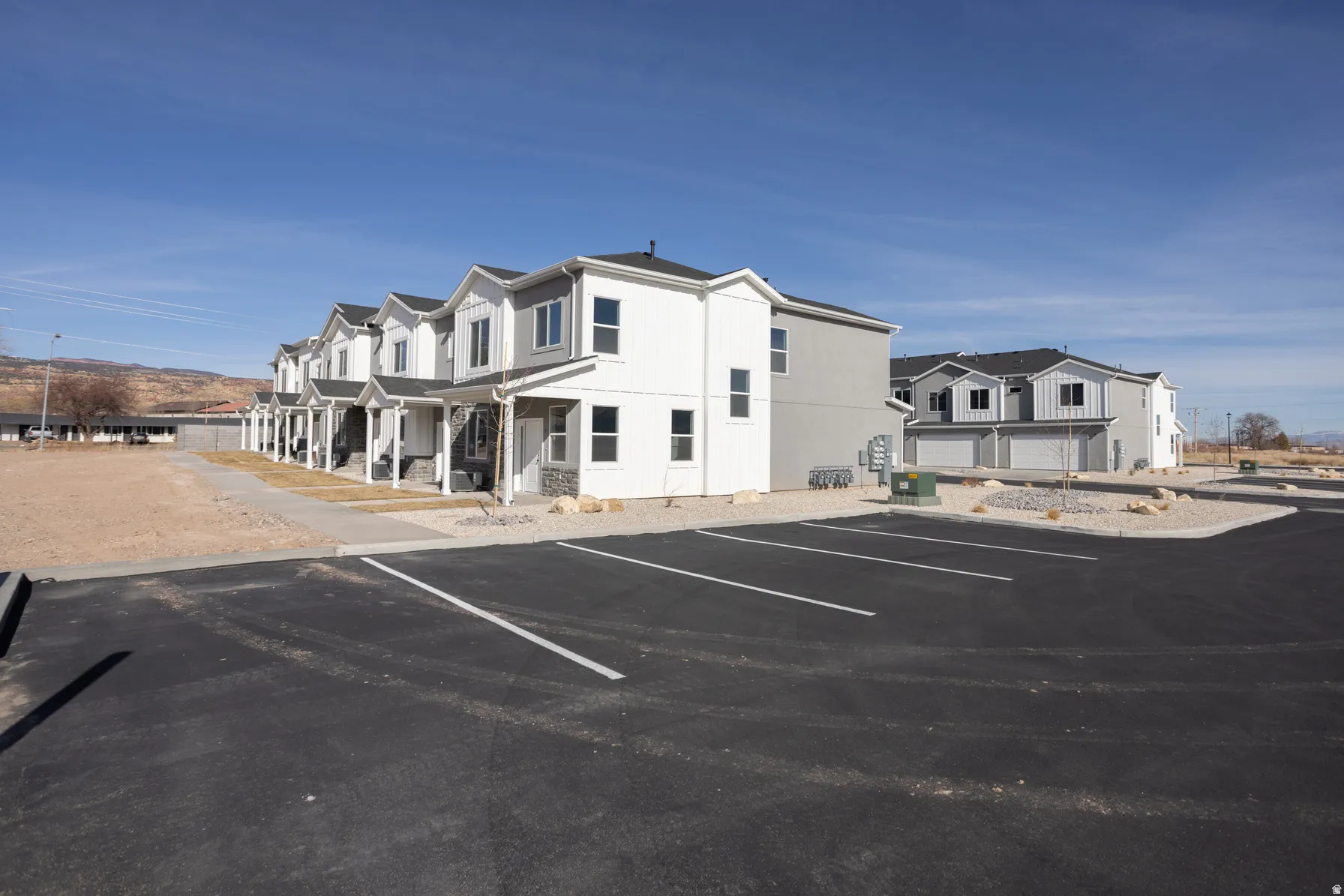 Newly constructed residential buildings featuring two-story designs, covered front porches, and partial stone veneer accents