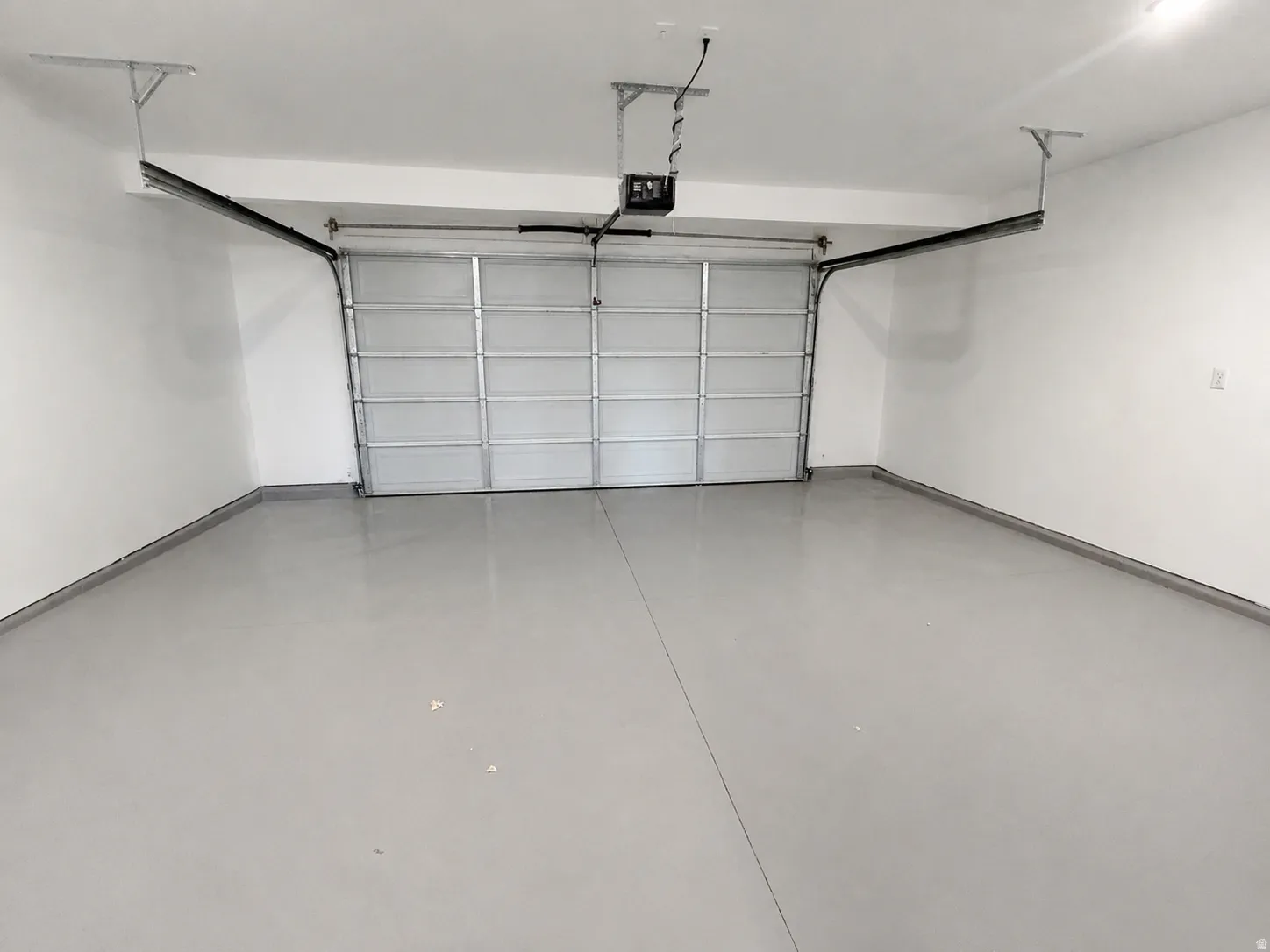 Spacious garage featuring a sectional garage door, light gray epoxy flooring, and white painted walls