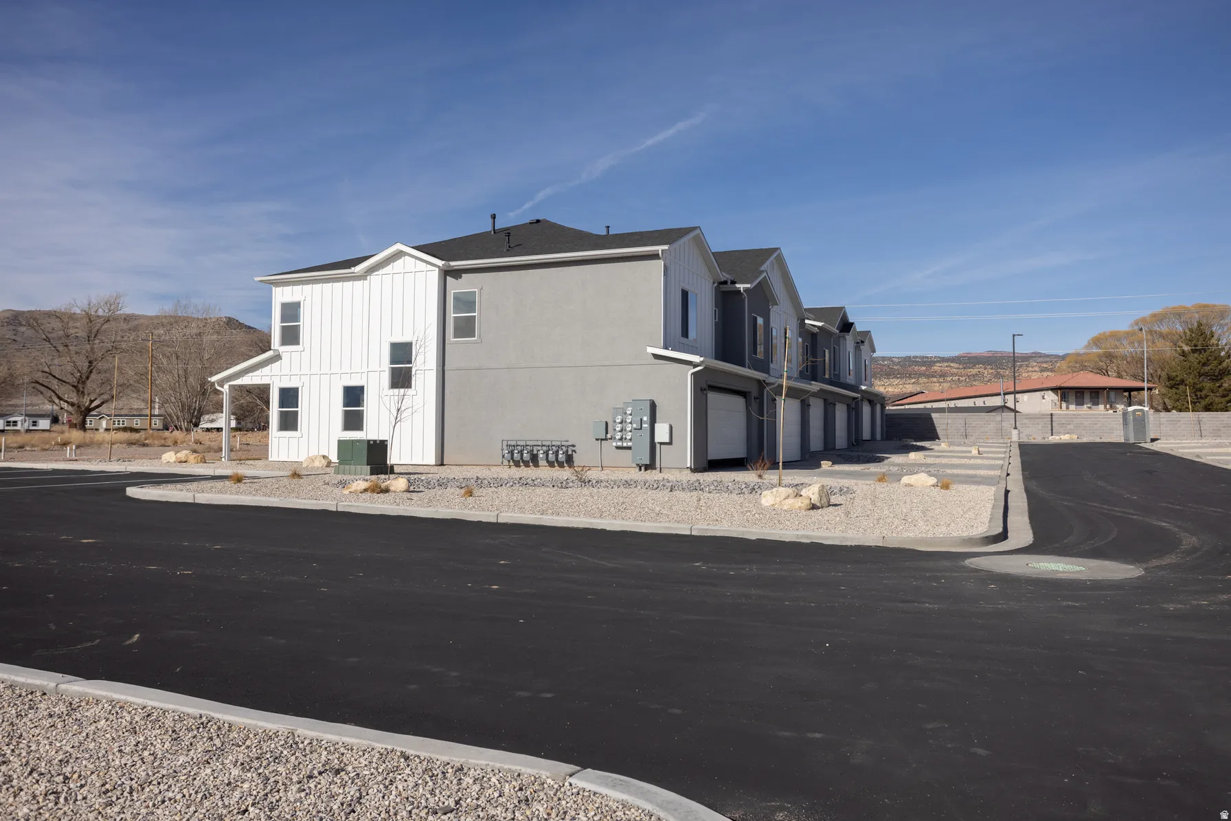 Modern multi-unit property with a combination of vertical white siding and gray stucco exterior finishes