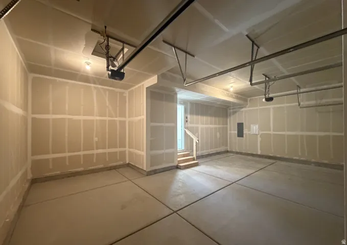 Spacious garage with concrete flooring, exposed drywall, and two automatic garage door openers