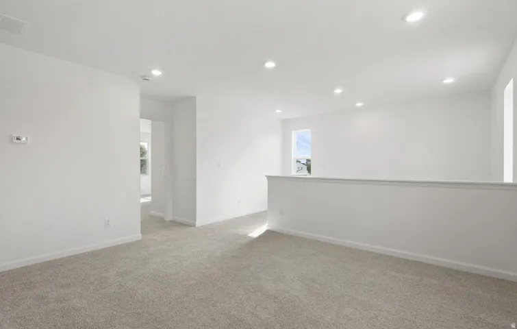 Carpeted flooring, recessed lighting, white painted walls, and a half-wall partition