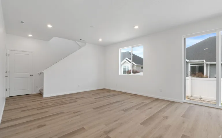 Spacious living area featuring wood-finish flooring, recessed lighting, and a modern sliding glass door