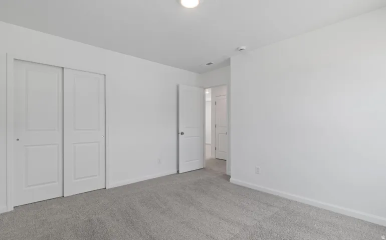 Recessed ceiling light, neutral wall paint, gray carpeting, white baseboards, and white interior doors