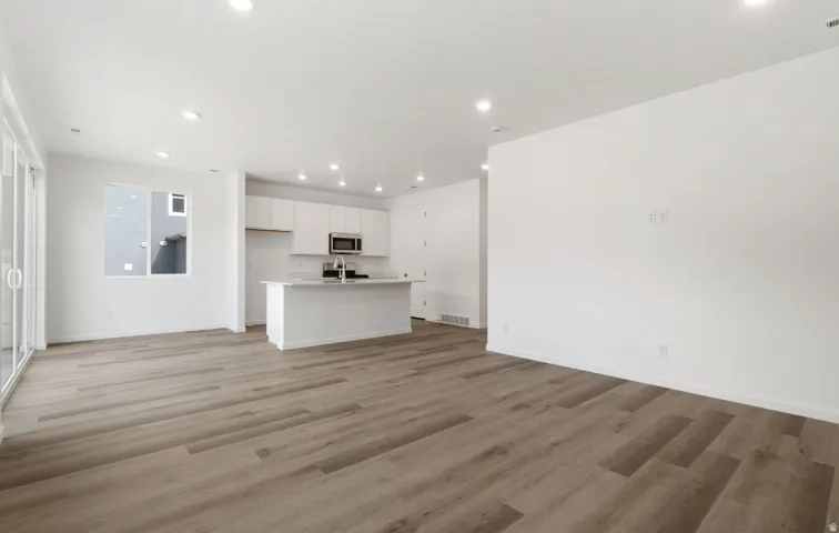 Open-concept living area featuring wood-finish flooring, recessed lighting, and sliding glass doors