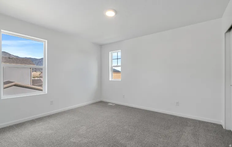 White-painted walls with recessed lighting, gray carpeting, and two windows