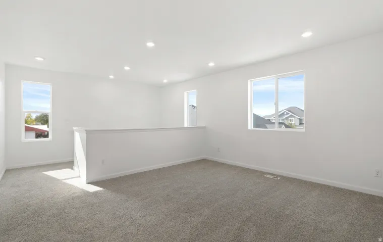 Bright open space featuring multiple windows, recessed lighting, and neutral carpeting