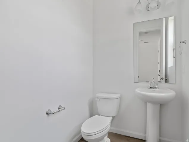 Pedestal sink with chrome faucet, wall-mounted mirror, and overhead vanity lighting