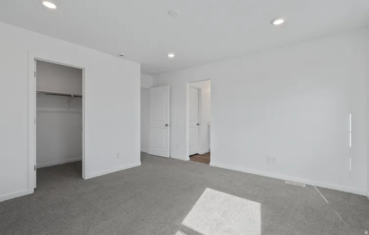 Recessed ceiling lighting illuminates the space, featuring gray carpeting and white walls