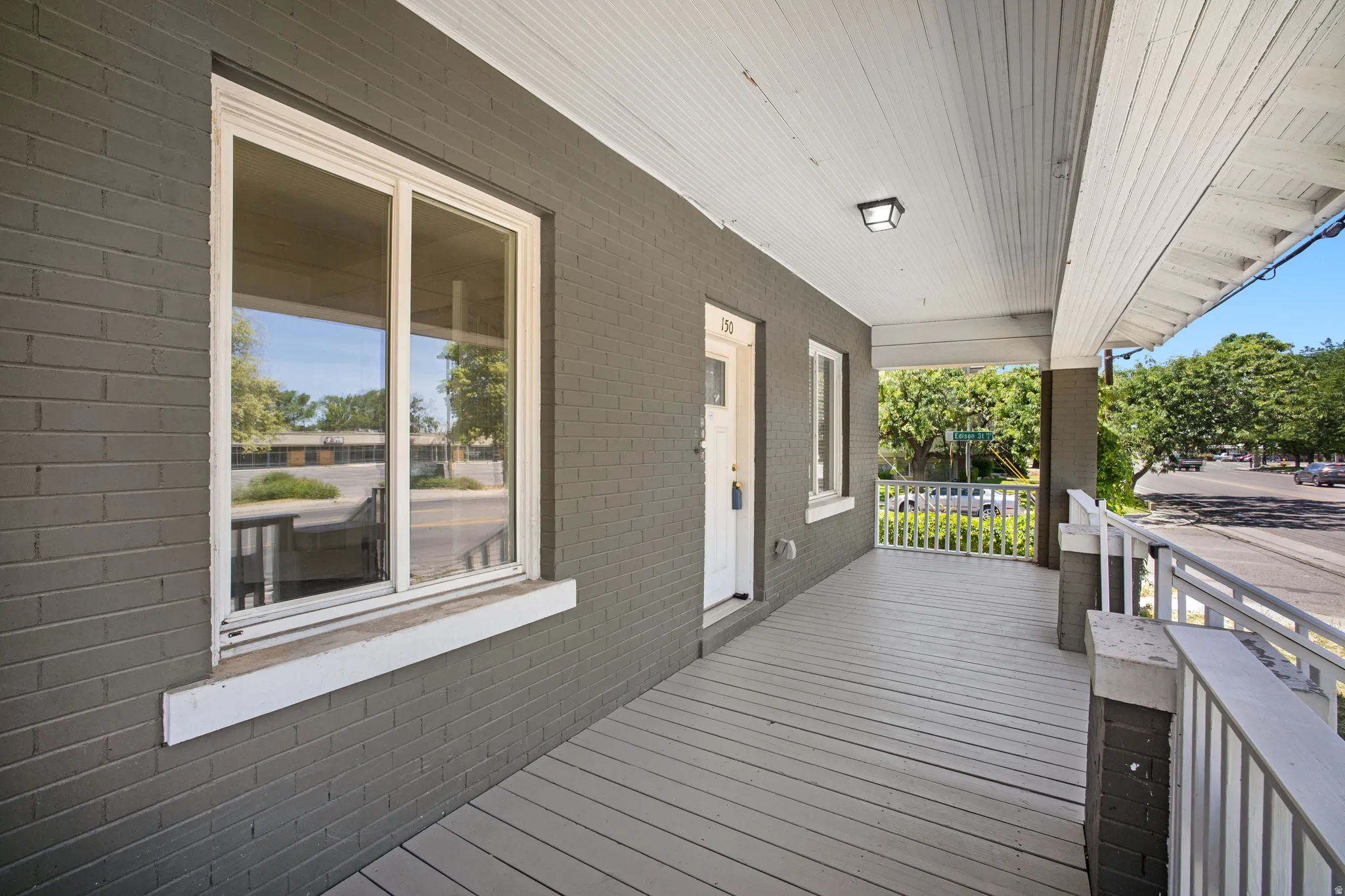 Spacious covered porch with plank flooring and painted brick facade