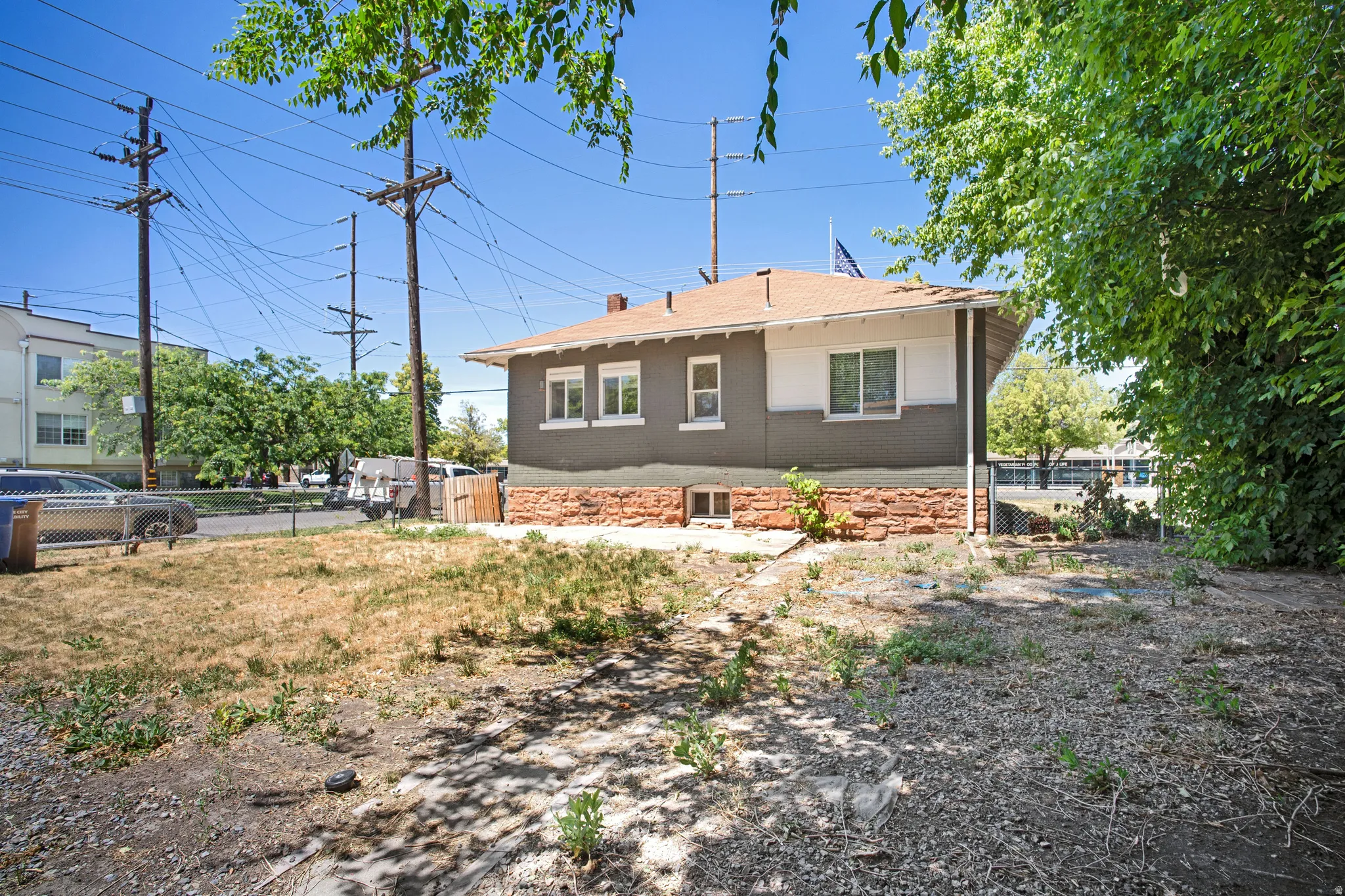 Residential property featuring a neutral-toned exterior with white trim windows and a red-toned roof