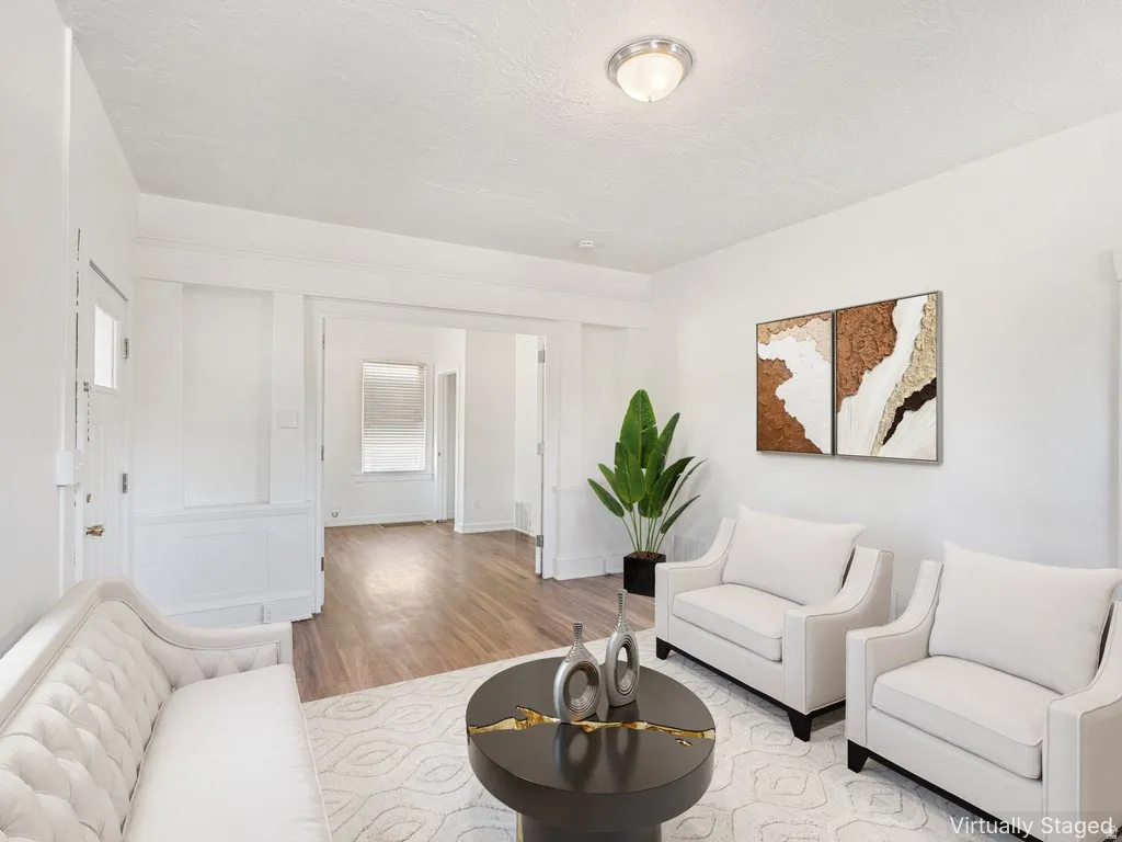 Spacious living area featuring light-toned walls, wood-finish flooring, recessed lighting, and an open doorway leading to another room
