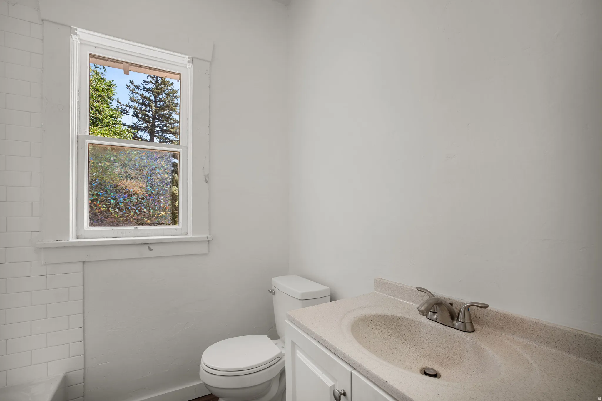 Bathroom featuring a white vanity with an integrated sink, brushed nickel faucet, and a white toilet