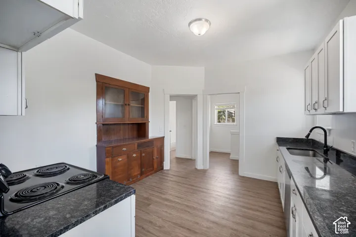 Kitchen featuring wood-finish flooring, white cabinetry, and dark countertops