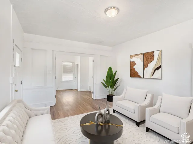 Spacious living area featuring light-toned walls, wood-finish flooring, recessed lighting, and an open doorway leading to another room