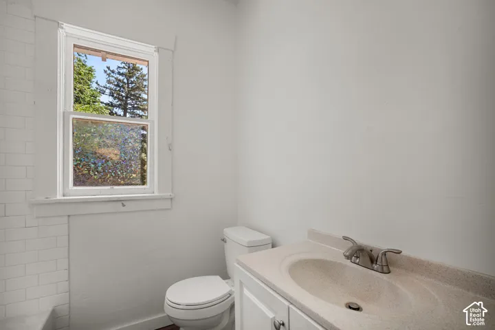 Bathroom featuring a white vanity with an integrated sink, brushed nickel faucet, and a white toilet