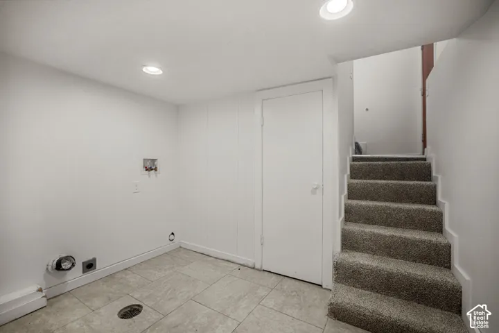 Lower level utility area featuring recessed lighting, tiled flooring, and laundry hookups