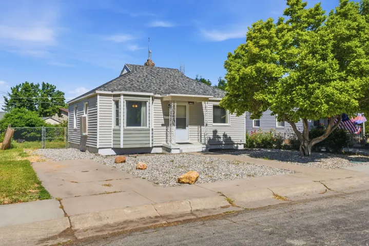 Angled exterior view showcasing curb appeal, low-maintenance front yard, mature tree, and driveway parking.