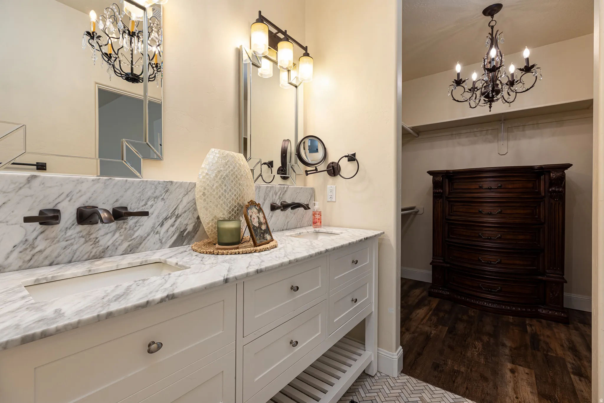 Double vanity featuring integrated sinks, substantial stone countertops with a matching backsplash, and wall-mounted faucets