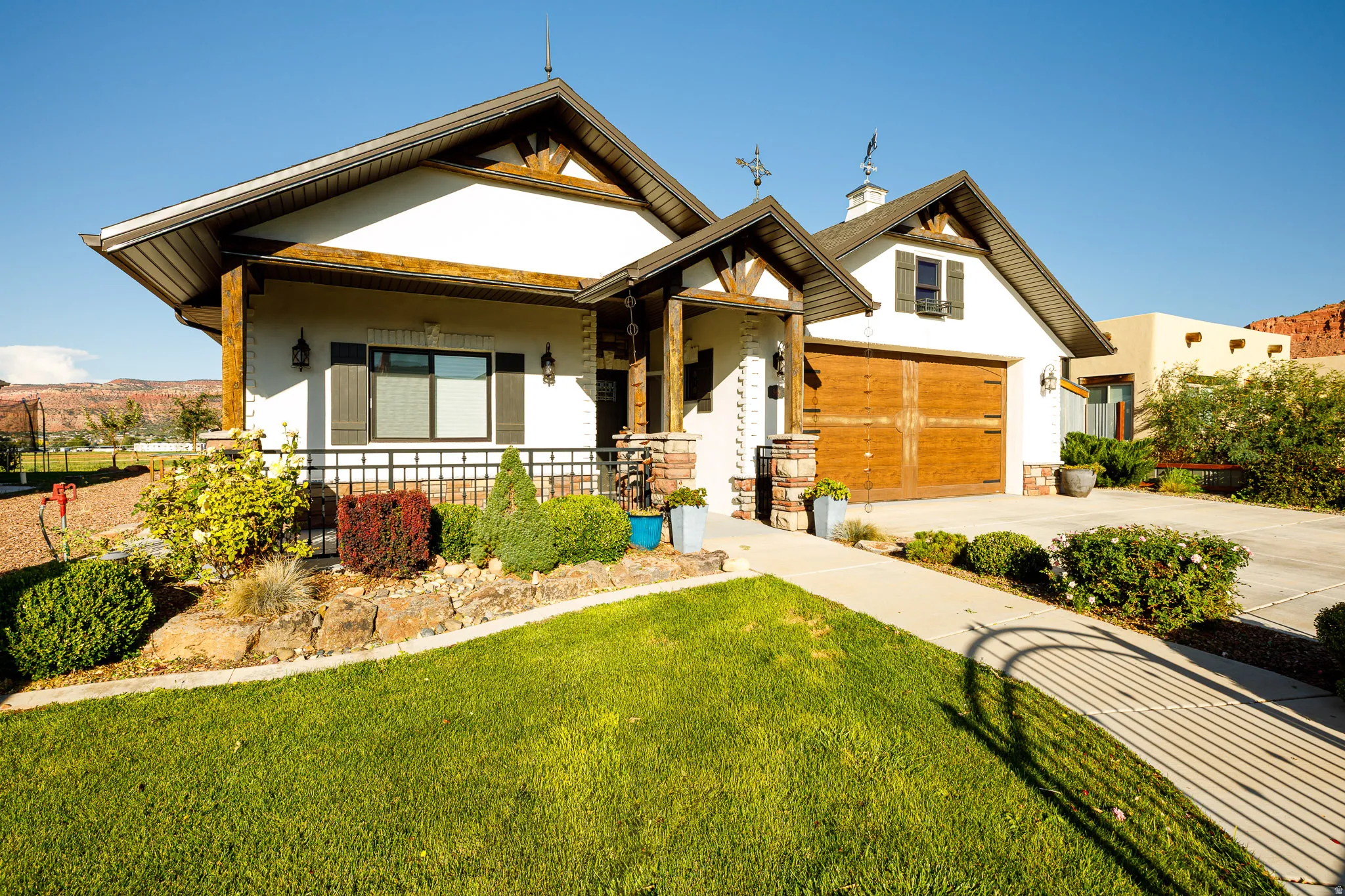 Contemporary stucco exterior featuring a prominent wood-finish garage door, gabled rooflines, and decorative wood-beam accents