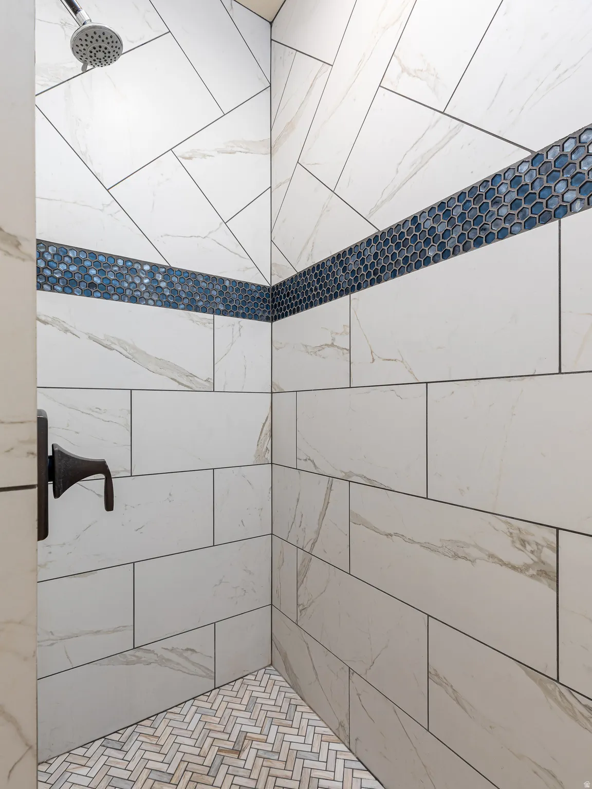 Tiled shower enclosure featuring a dark bronze shower fixture and rain shower head