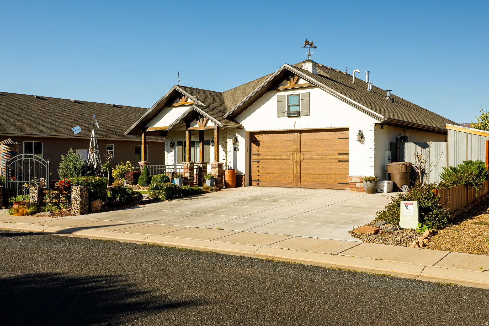 Single-story residence featuring a wood-finish garage door, white stucco exterior, and a gabled roofline