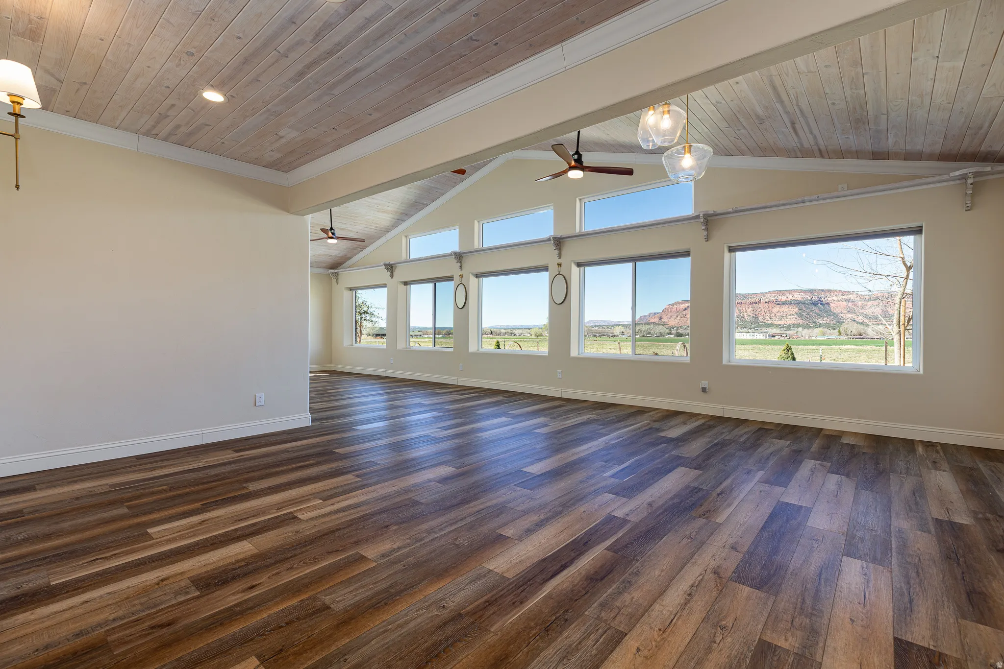 Spacious interior featuring wood-finish flooring, light-toned walls, and a vaulted ceiling with wood paneling