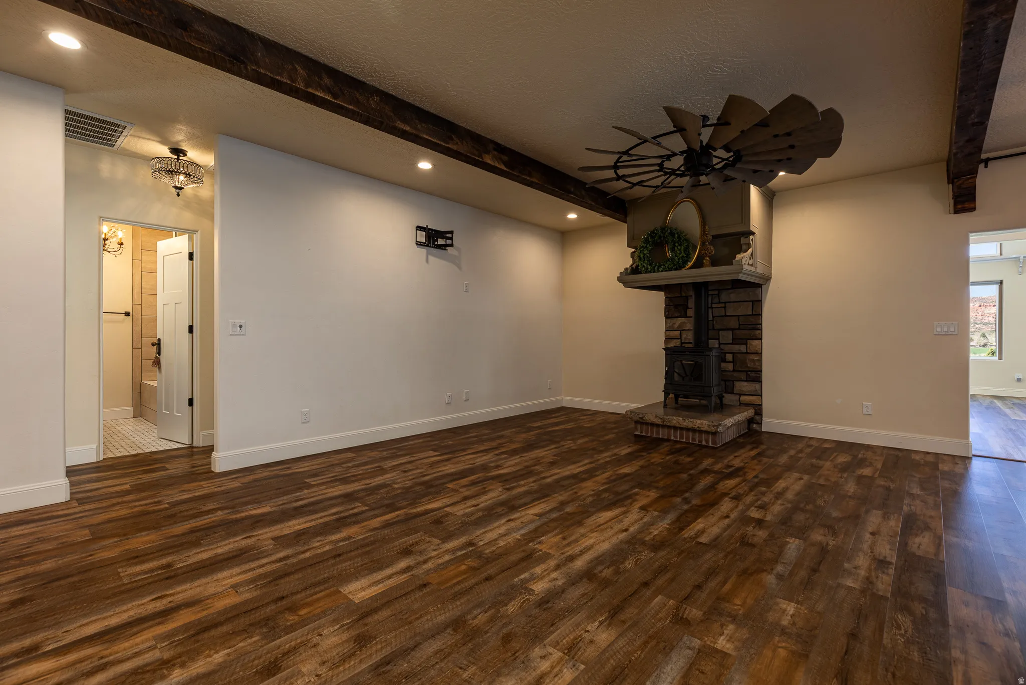 Spacious living area featuring wood-finish flooring, exposed ceiling beams, and recessed lighting