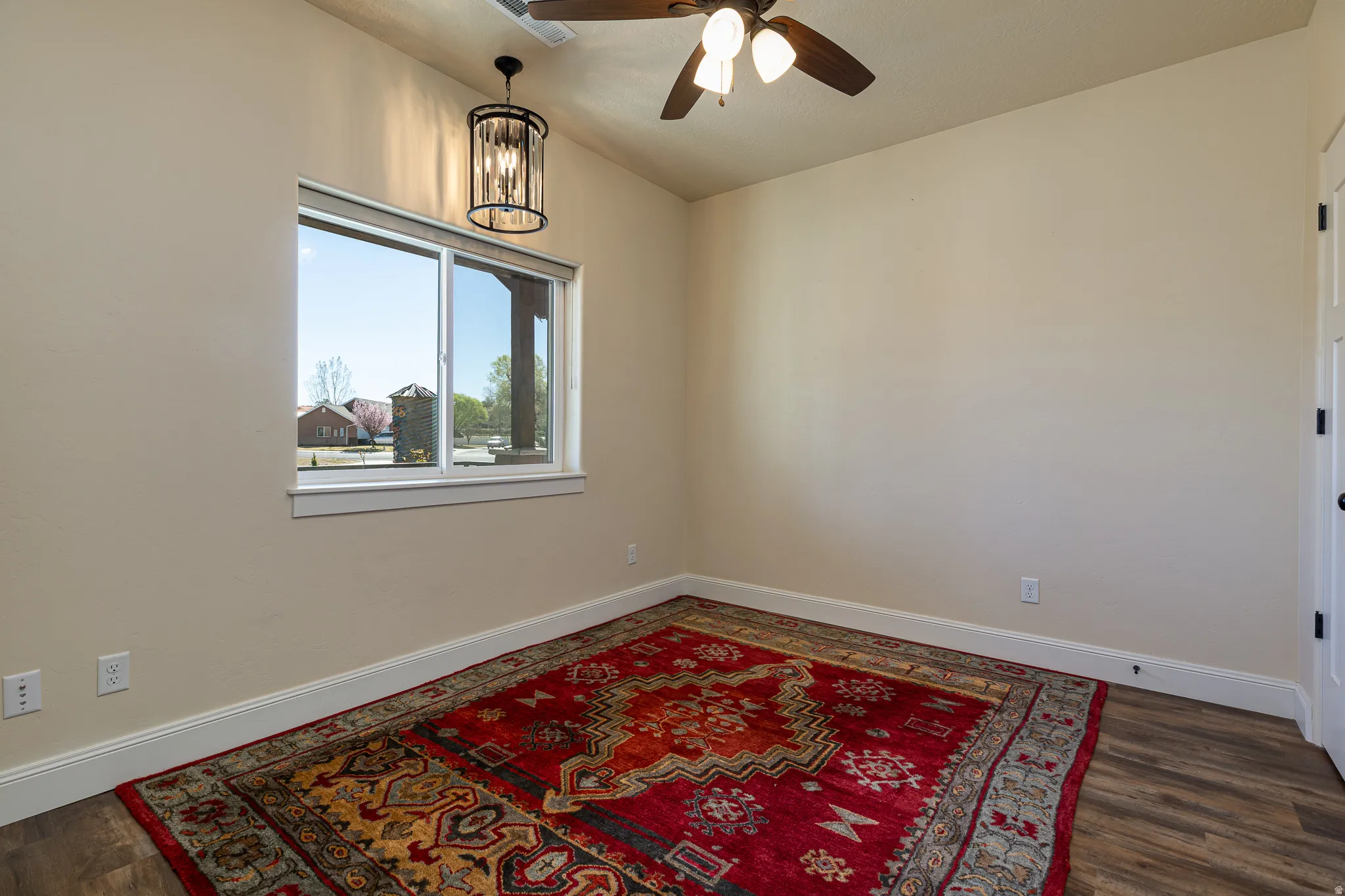 Room featuring wood-finish flooring, a window with exterior views, and a ceiling fan with integrated lighting