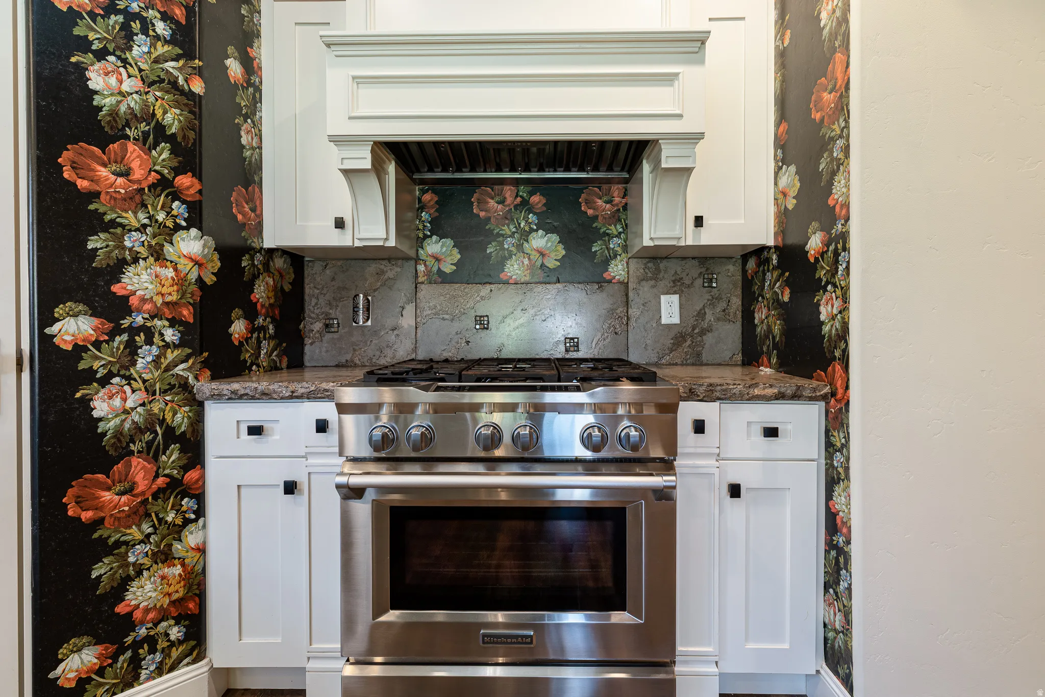 Stainless steel range with a gas cooktop, granite-style countertops, and white shaker-style cabinetry featuring matte black hardware