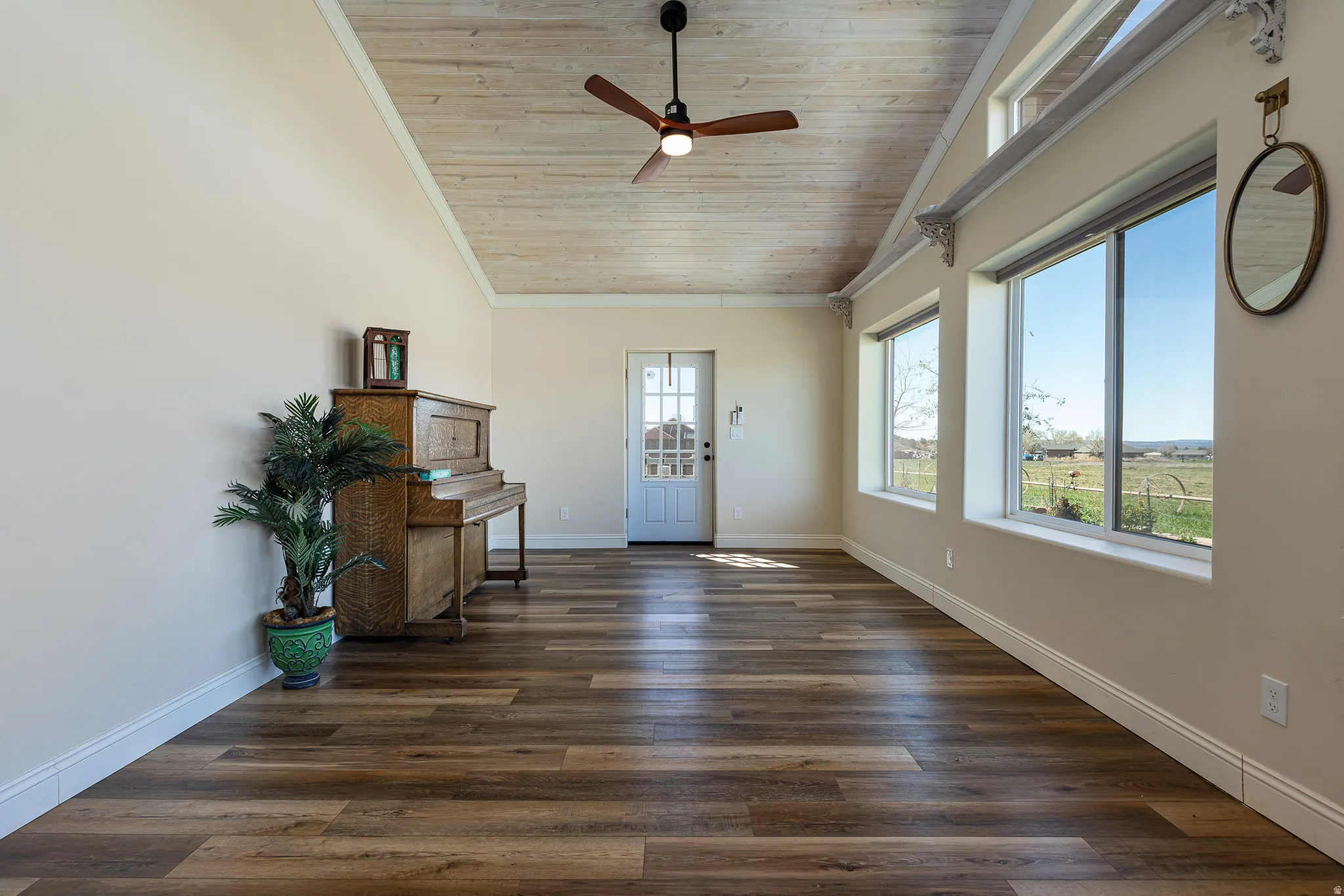 Spacious room featuring wood-finish flooring, a vaulted ceiling with a wood plank finish, a ceiling fan, and multiple windows