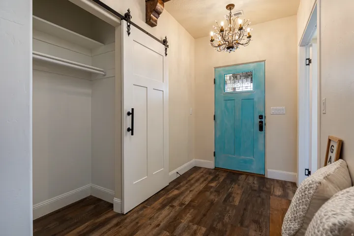 Entryway featuring a turquoise door with leaded glass, wood-finish flooring, and a chandelier