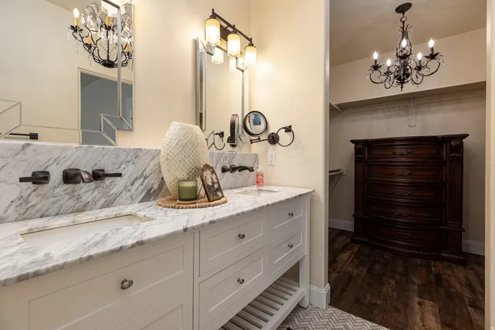 Double vanity featuring integrated sinks, substantial stone countertops with a matching backsplash, and wall-mounted faucets