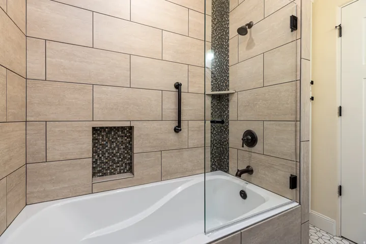 Tiled shower and tub combination featuring clear glass enclosure