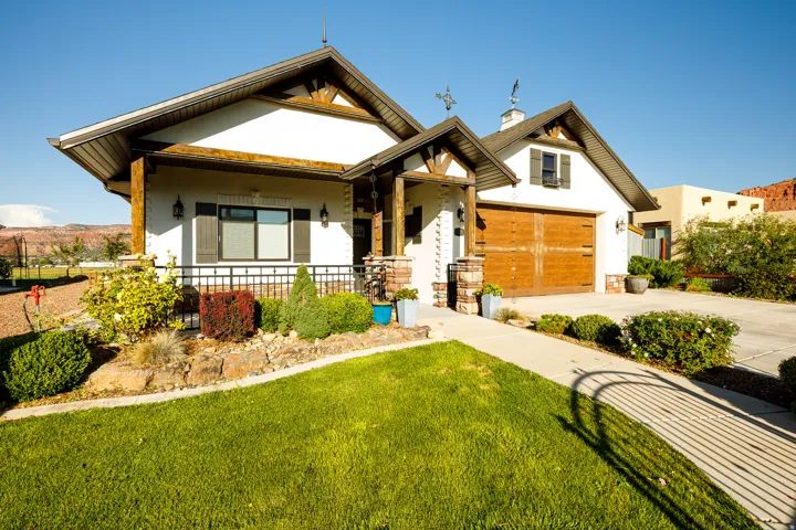 Contemporary stucco exterior featuring a prominent wood-finish garage door, gabled rooflines, and decorative wood-beam accents