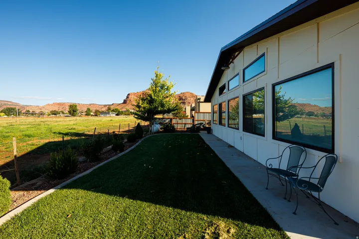 Exterior wall with multiple large windows, a continuous concrete walkway, and a manicured lawn border