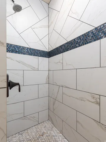 Tiled shower enclosure featuring a dark bronze shower fixture and rain shower head