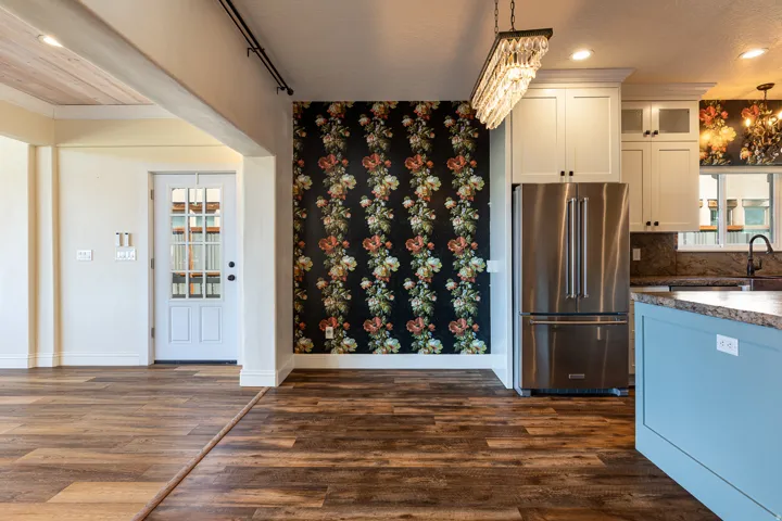 Wood-finish flooring throughout, complemented by a white glass-paneled entry door and a floral accent wall
