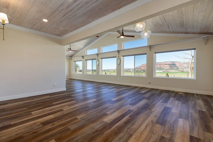 Spacious interior featuring wood-finish flooring, light-toned walls, and a vaulted ceiling with wood paneling