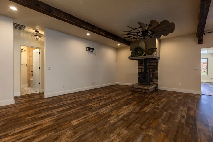 Spacious living area featuring wood-finish flooring, exposed ceiling beams, and recessed lighting