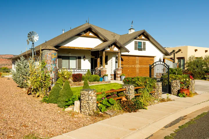 Craftsman-style home featuring a white facade with dark trim, a prominent garage door with wood-finish paneling, and a covered front porch with stone columns