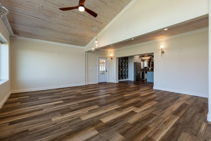 Spacious room with wood-finish flooring, a vaulted ceiling with wood paneling, a ceiling fan, and recessed lighting