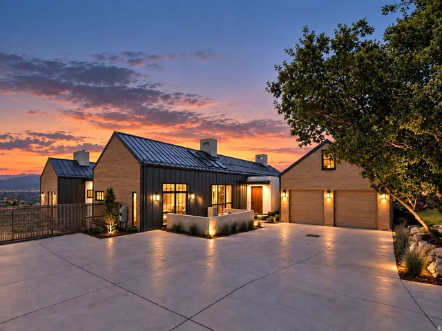 Modern architectural design with a standing seam metal roof, extensive exterior lighting, a concrete driveway, and a two-car garage with wood-finish doors