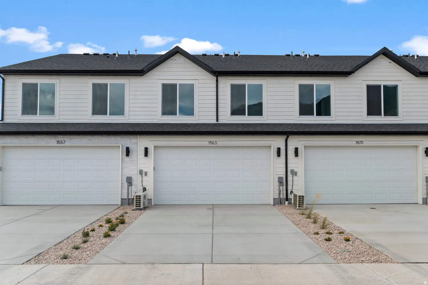 Contemporary townhome exterior featuring white horizontal siding and a dark shingled roof
