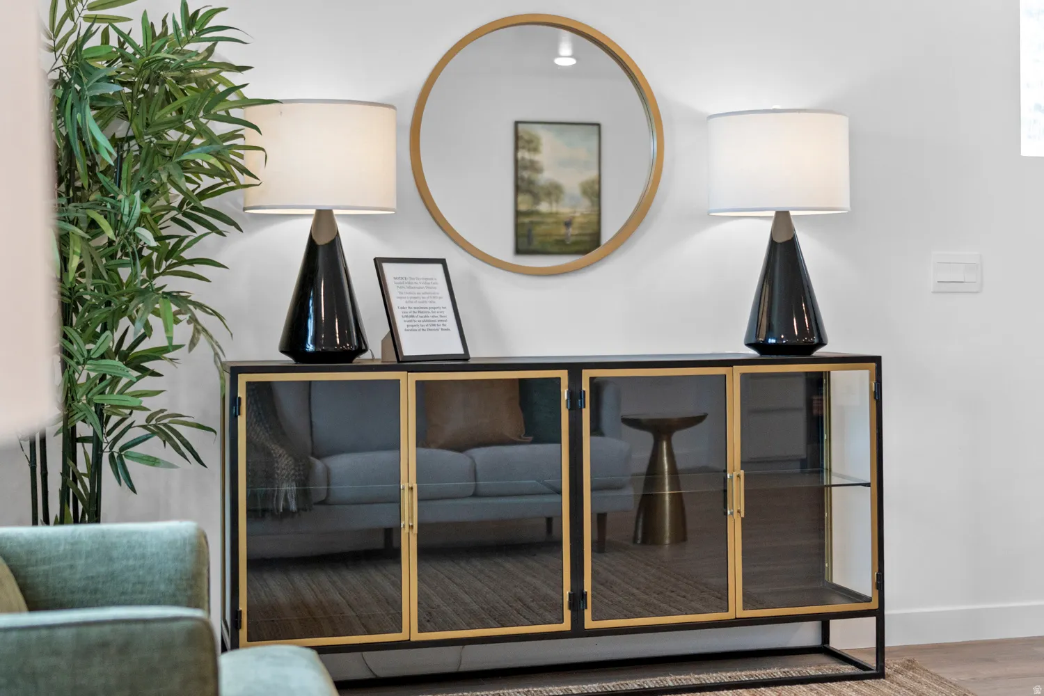 Accent cabinet featuring a black frame, gold-tone door trim, and glass paneling