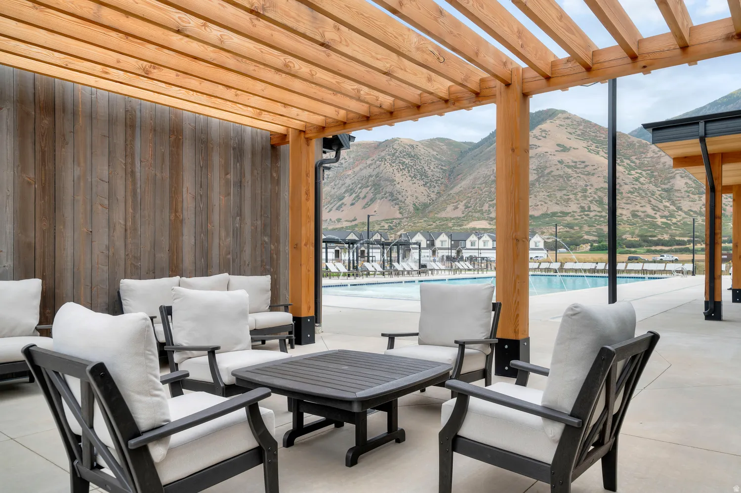Outdoor lounge area featuring a wooden pergola and a board-and-batten accent wall