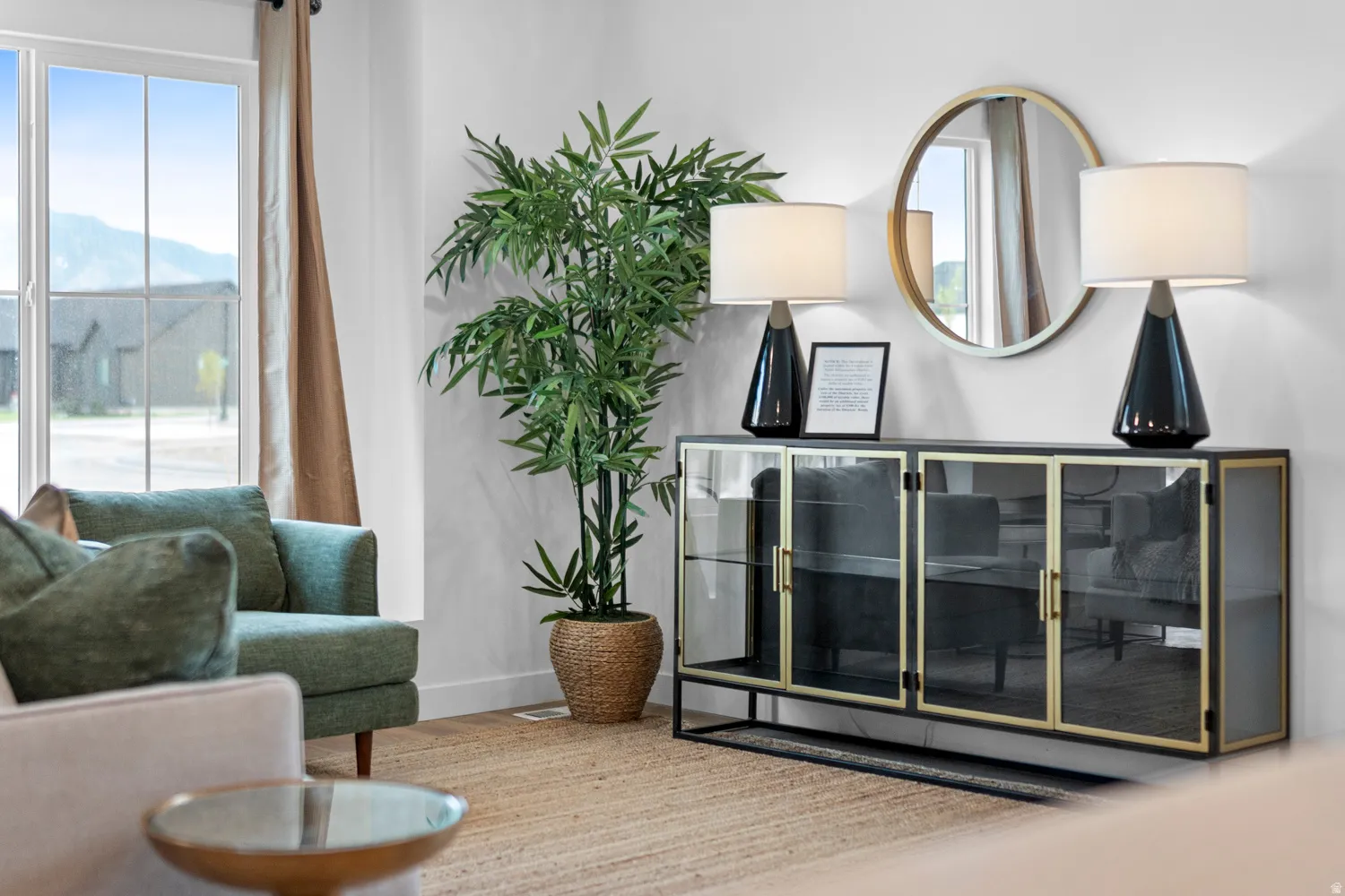 Bright interior space featuring a large window with mountain scenery, a woven natural fiber area rug, and a built-in display cabinet with glass doors and a gold-tone frame
