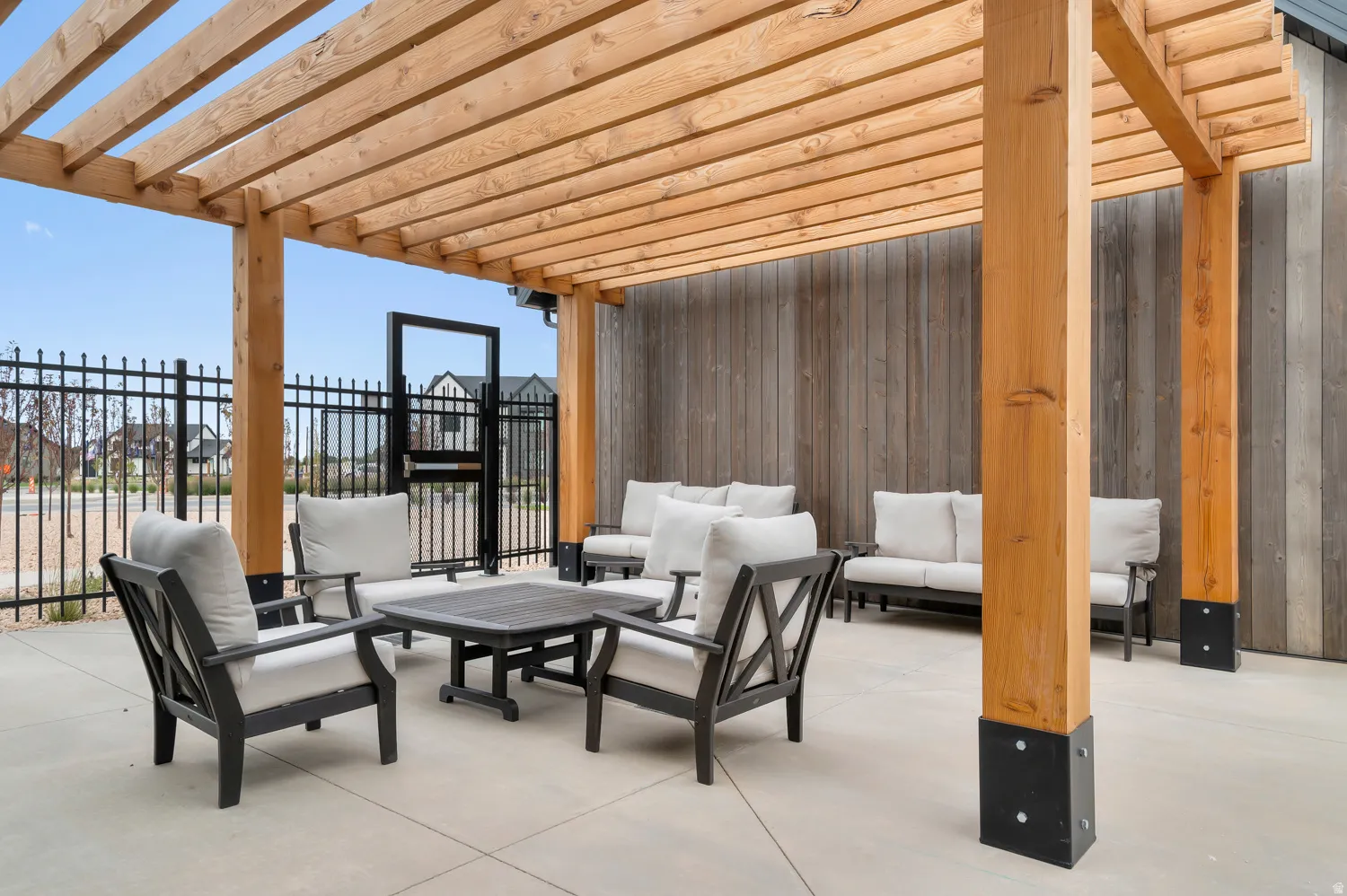 Outdoor patio area featuring a slatted wood pergola and a wood-paneled accent wall