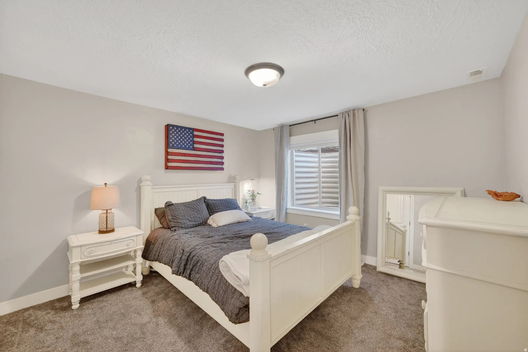 Carpeted room with light gray walls, a single window, and a flush-mount ceiling light fixture
